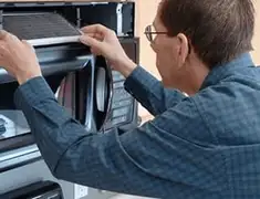 Appliance repair technician replacing a microwave vent filter in St Paul, MN