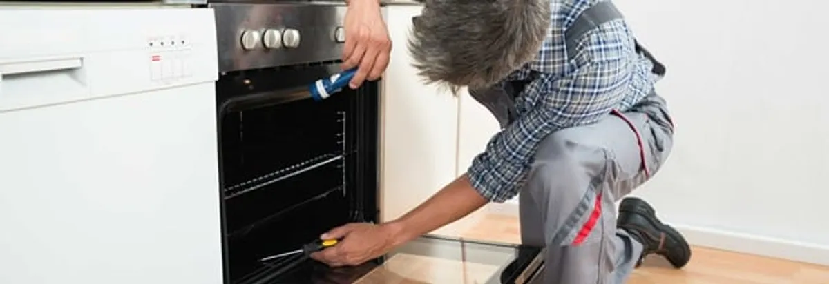 Oven repair technician inspecting and servicing an electric oven in St Paul, MN