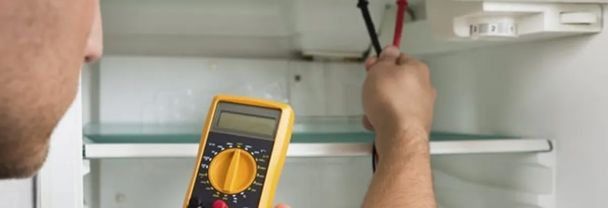 Refrigerator repair technician testing electrical components with a multimeter in St Paul, MN